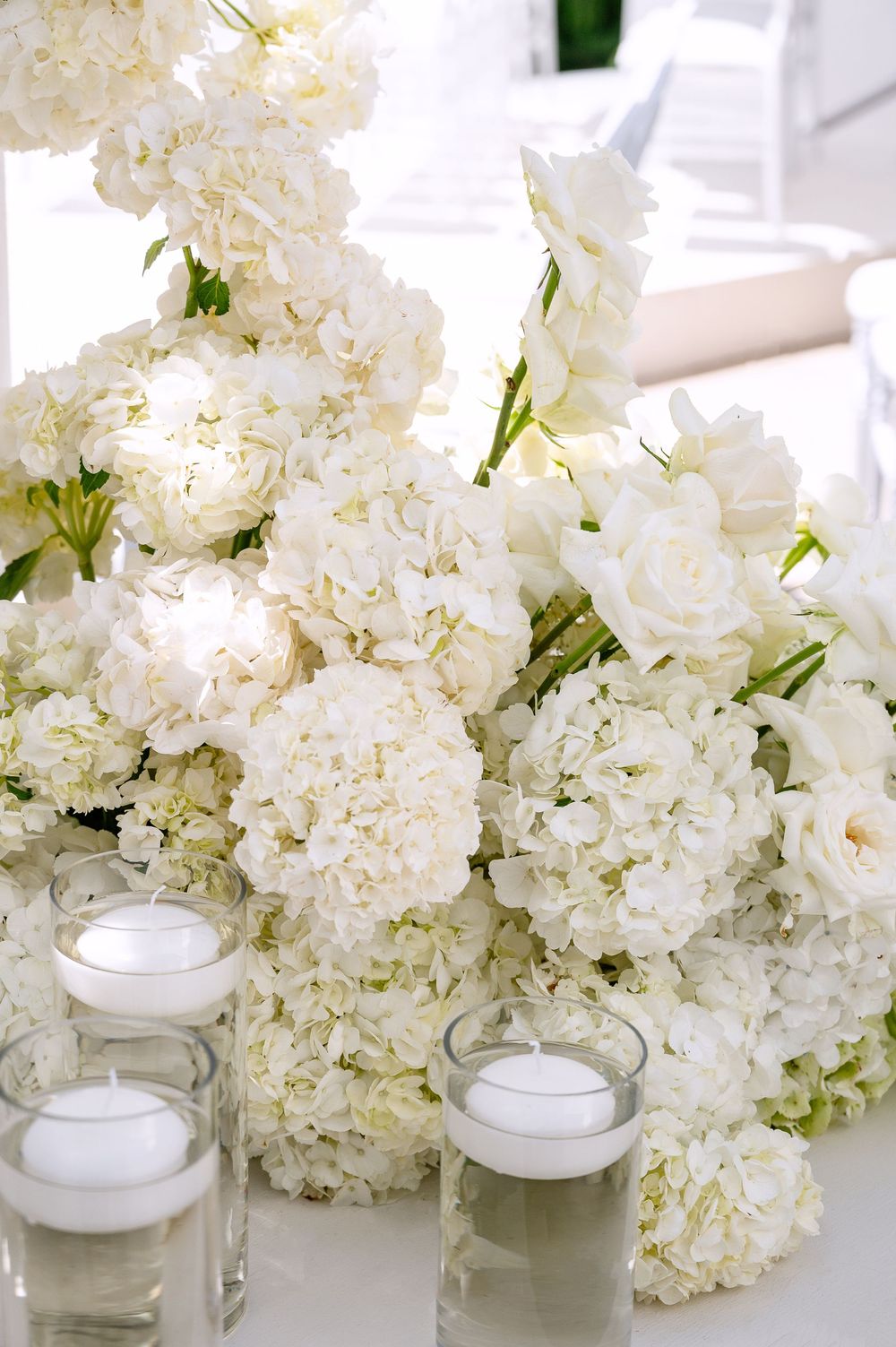 White hydrangea flower arrangements with glass votive candle holders create an elegant centerpiece display.