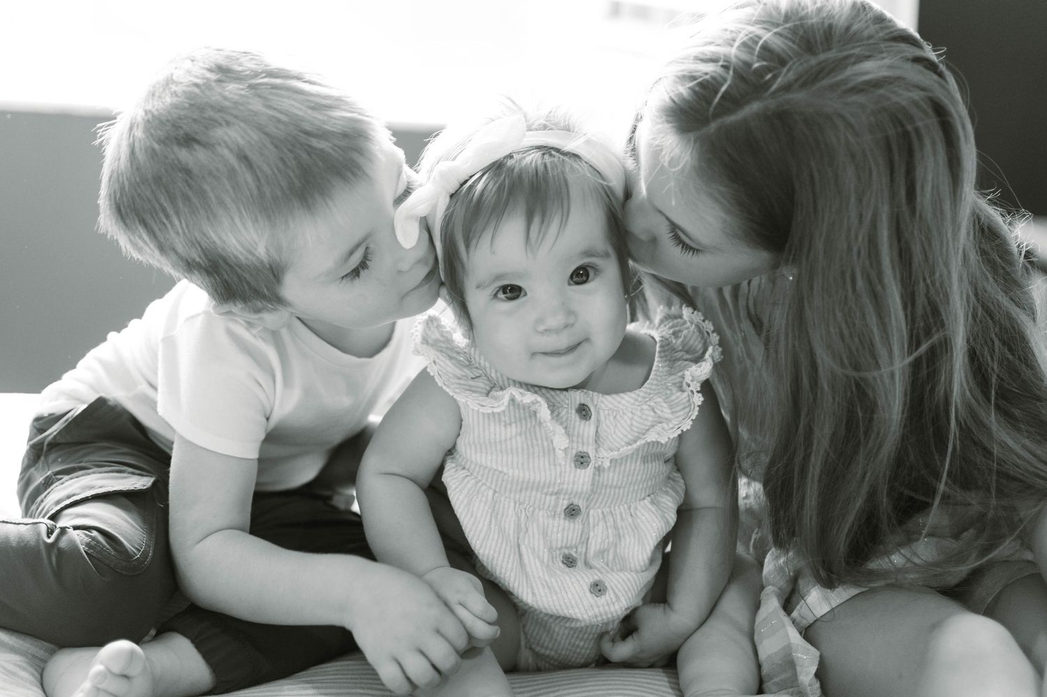 A tender black and white photograph capturing siblings sharing a sweet moment together.