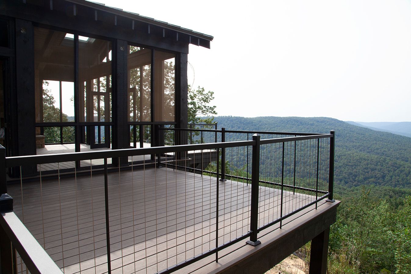 Panoramic view of a modern deck or balcony overlooking a forested mountain landscape.