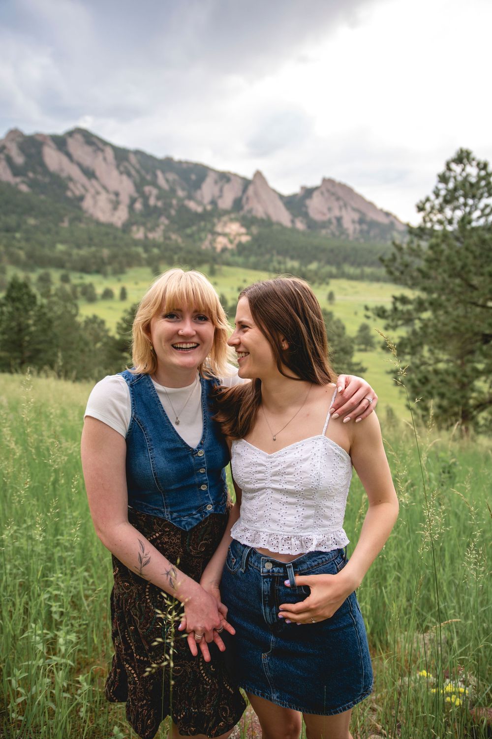 Happy couple sharing joyful moments together in a scenic mountain meadow with the Flatirons visible in background.