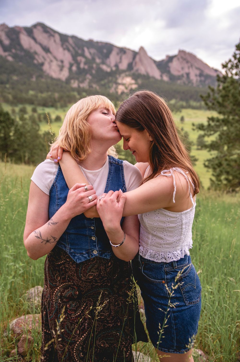 Two people share an intimate moment together in front of the iconic Flatirons rock formation in Boulder, Colorado.