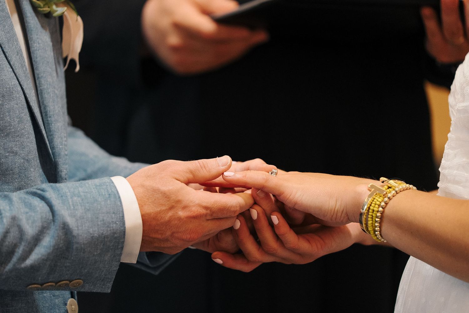 Detailed close-up sequence showing two hands exchanging wedding rings during a marriage ceremony.