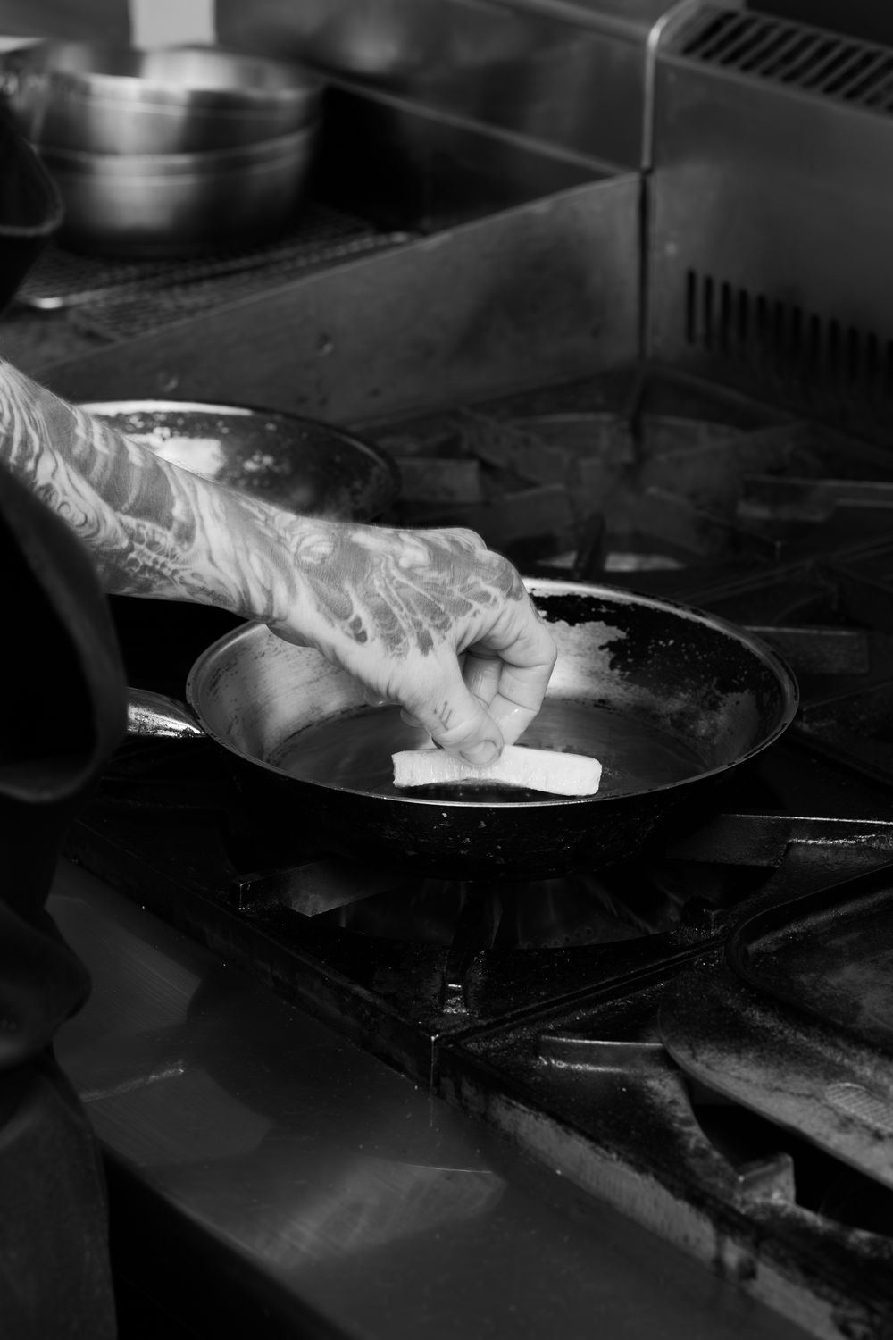 Chef wearing protective gloves prepares food on a dark surface in a commercial kitchen.