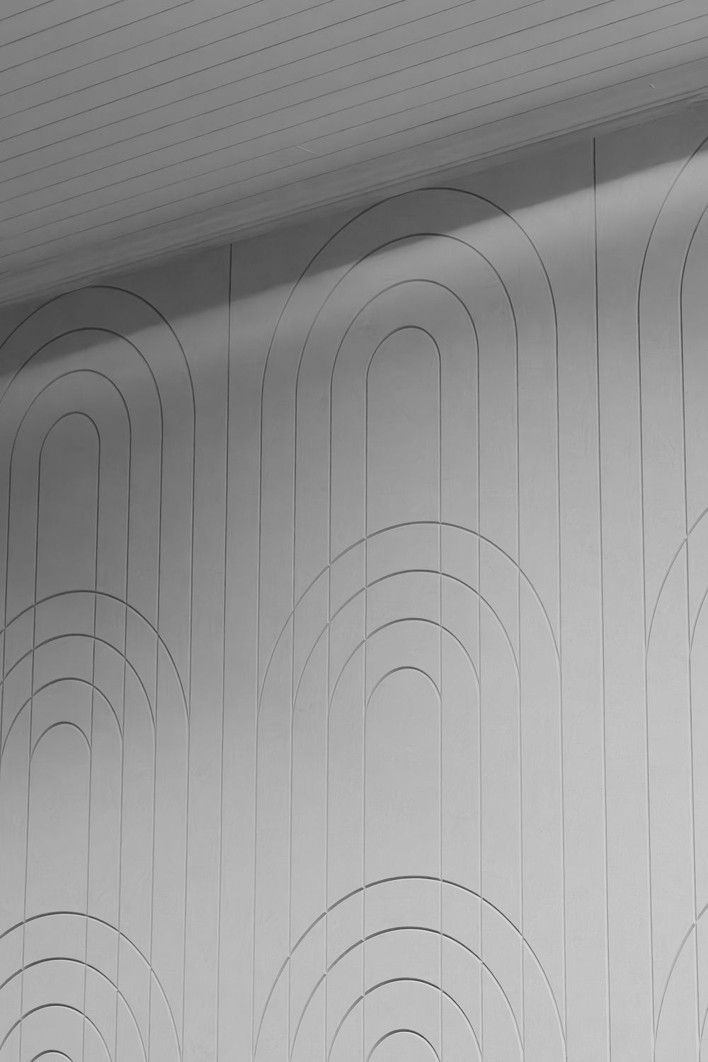 Abstract black and white architectural detail showing curved arches and lines on a white wall with geometric patterns.