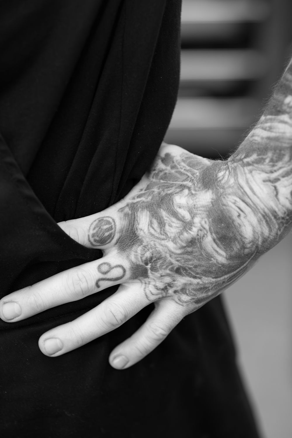 A set of six black and white photos showing detailed close-up views of hand tattoos with intricate art designs.