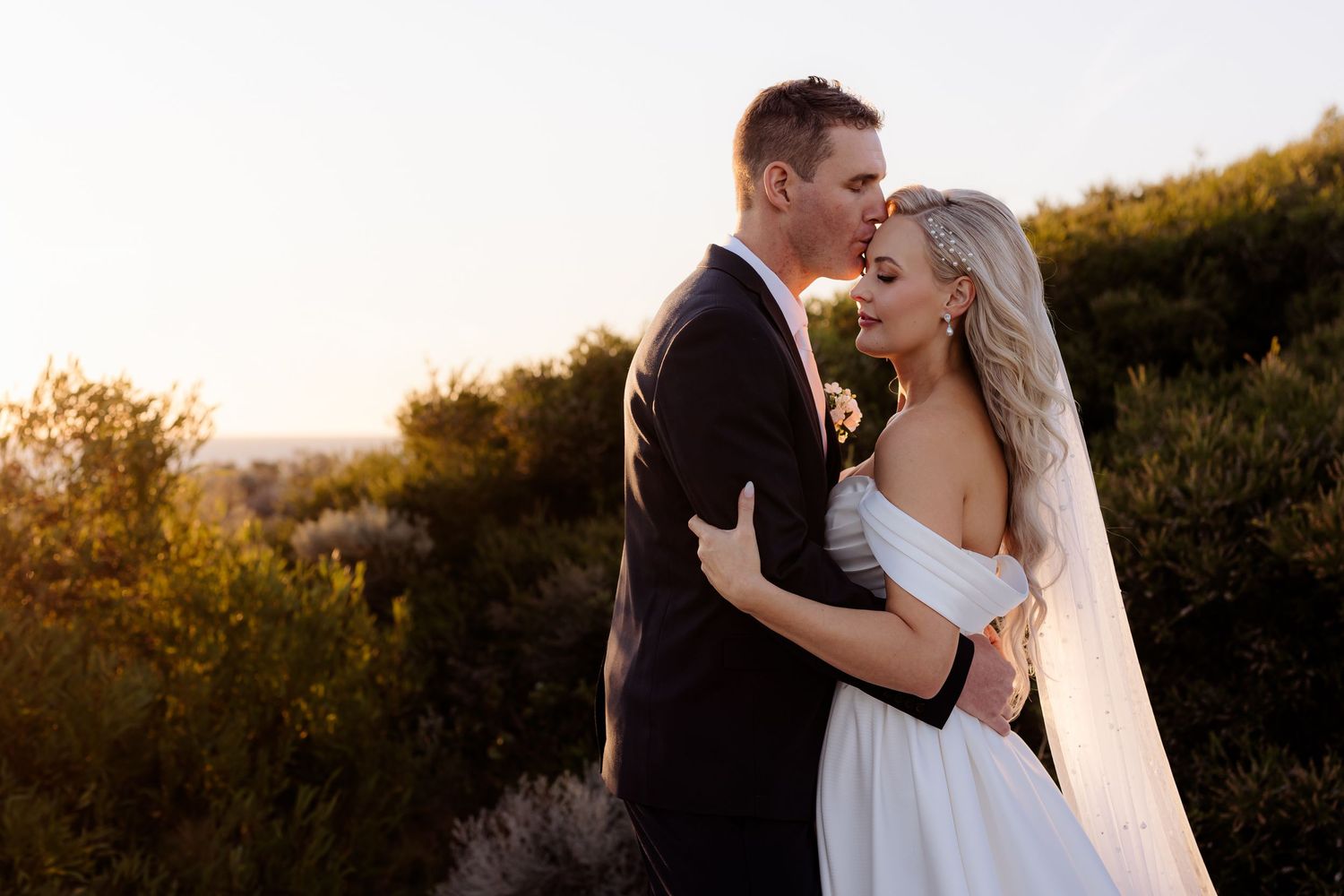 A couple shares an intimate embrace during their sunset outdoor wedding photoshoot.