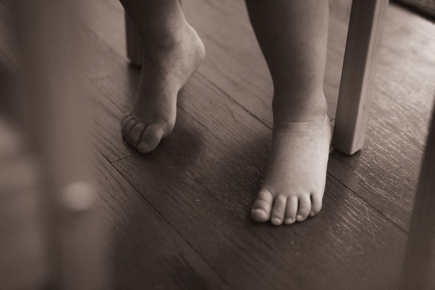 Bare feet stepping across a dark hardwood floor in a repeating sequence of images showing forward motion in Barrington