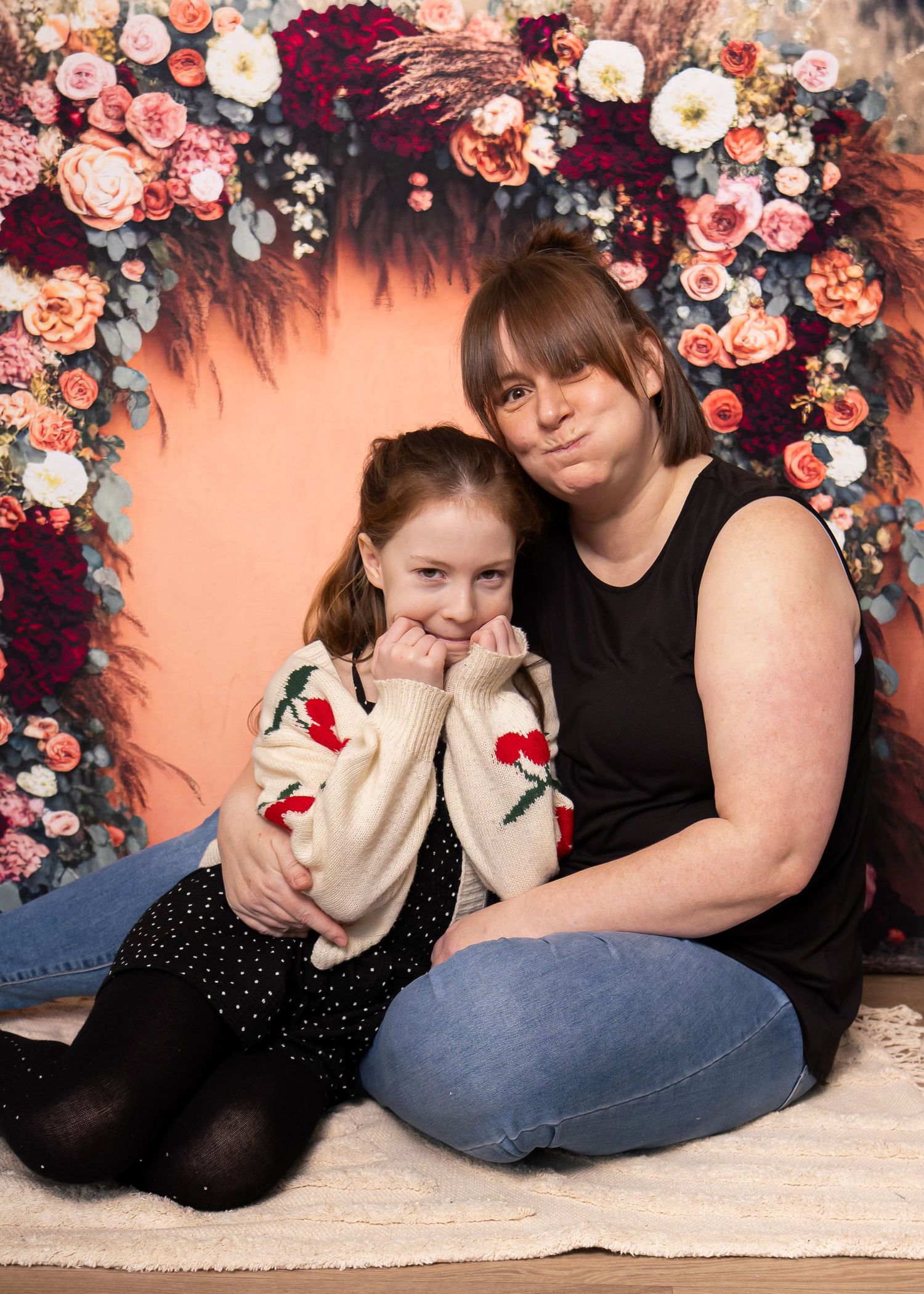 A floral backdrop photoshoot featuring people in casual attire posing together.