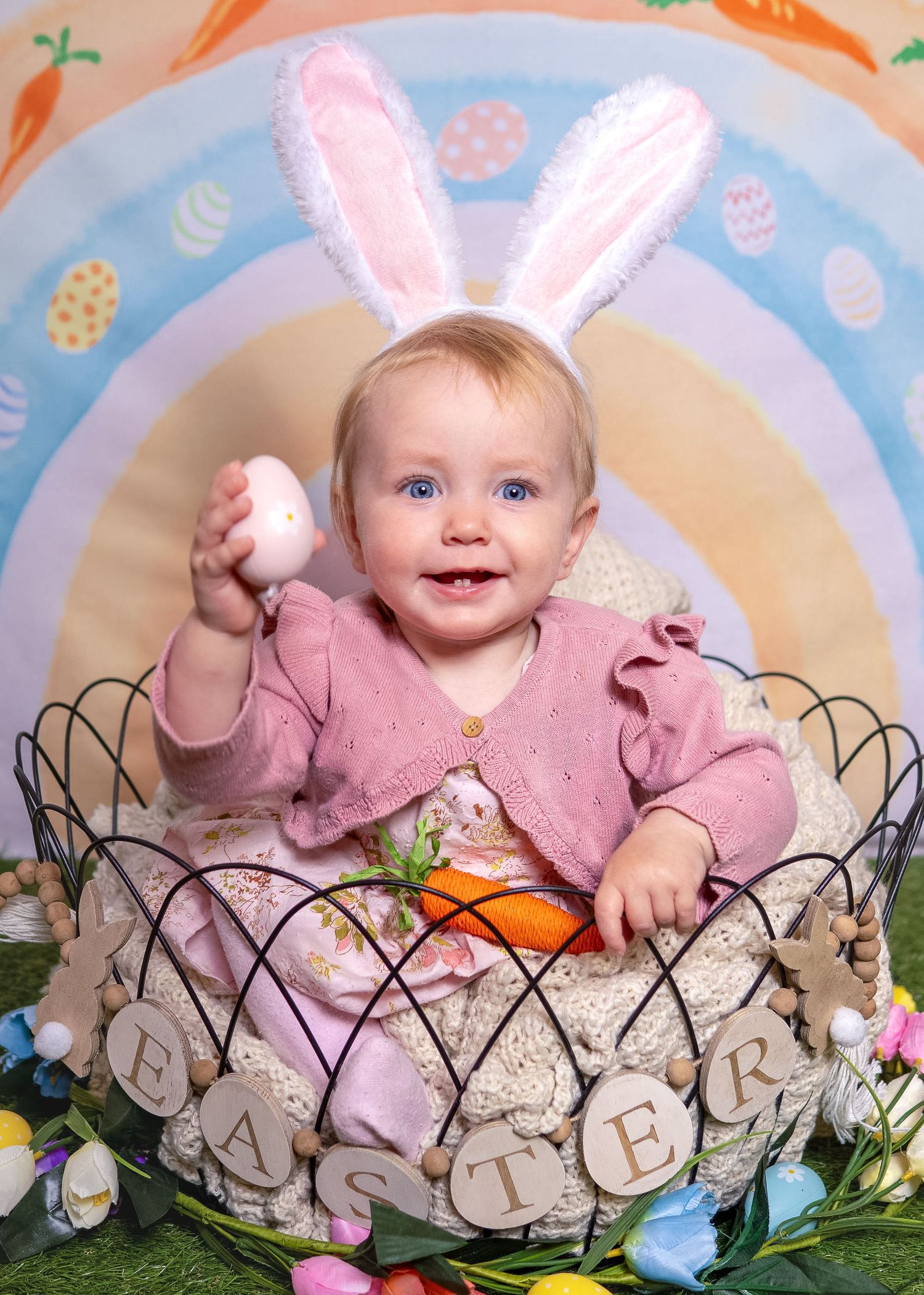 Easter Mini Session - Easter themed photo setup with decorative wire basket and bunny ears against pastel backdrop.