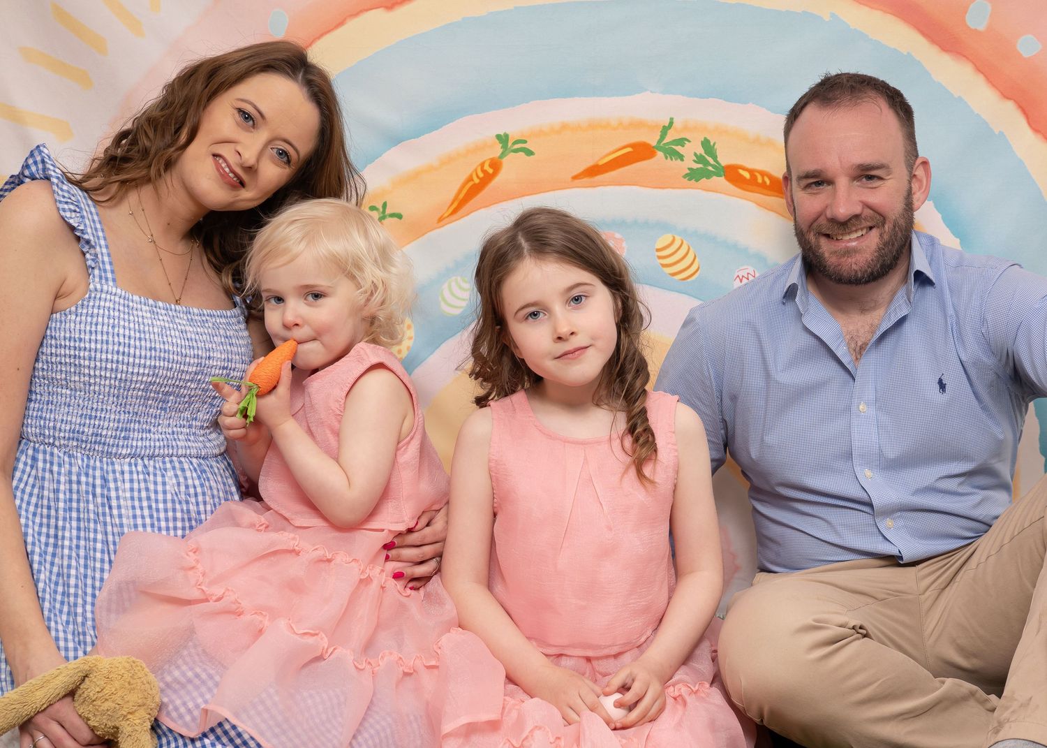 Easter Mini Session - A family portrait session with coordinated blue and pink outfits against a painted backdrop.