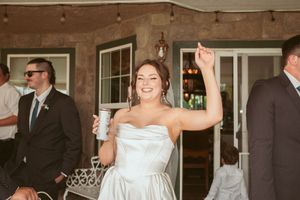 Wedding party celebrates during reception inside rustic venue with stone walls.