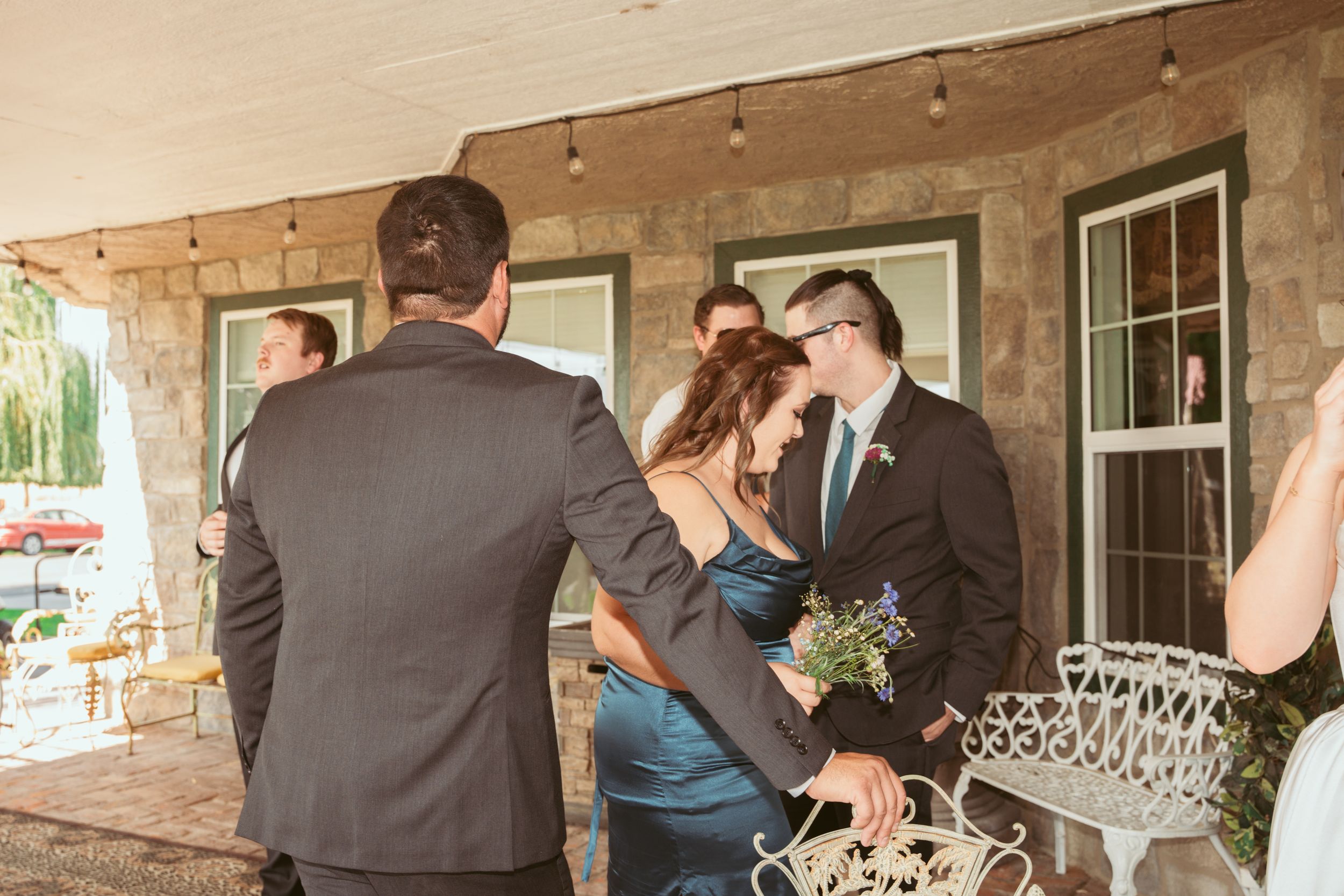 Wedding party and guests mingle under a covered outdoor venue during a celebration.
