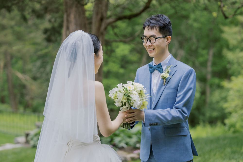Romantic wedding moment captured in a garden setting with a bouquet of white flowers.