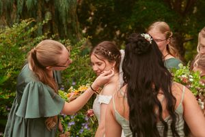 Wedding party laughing together outdoors in a garden setting.