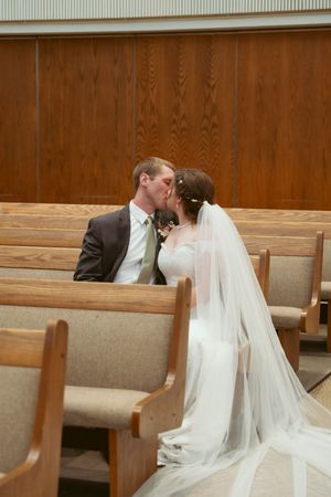 A touching moment between newlyweds sitting in wooden church pews.