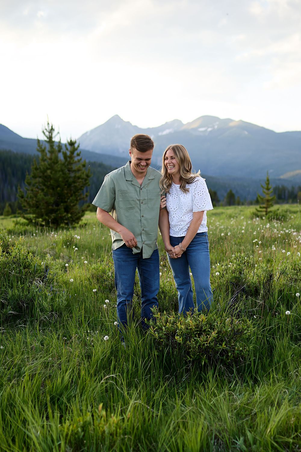 Couple enjoying a summer evening in a wildflower meadow with majestic mountain peaks in the background.