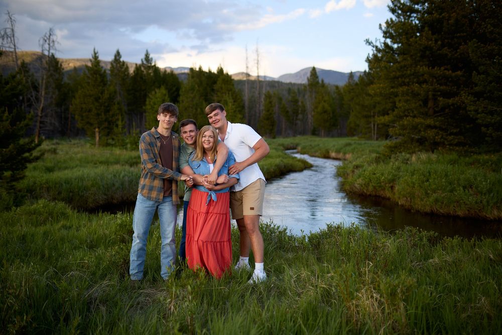 Mountains and forest provide a scenic backdrop for an outdoor family photoshoot along a winding river.