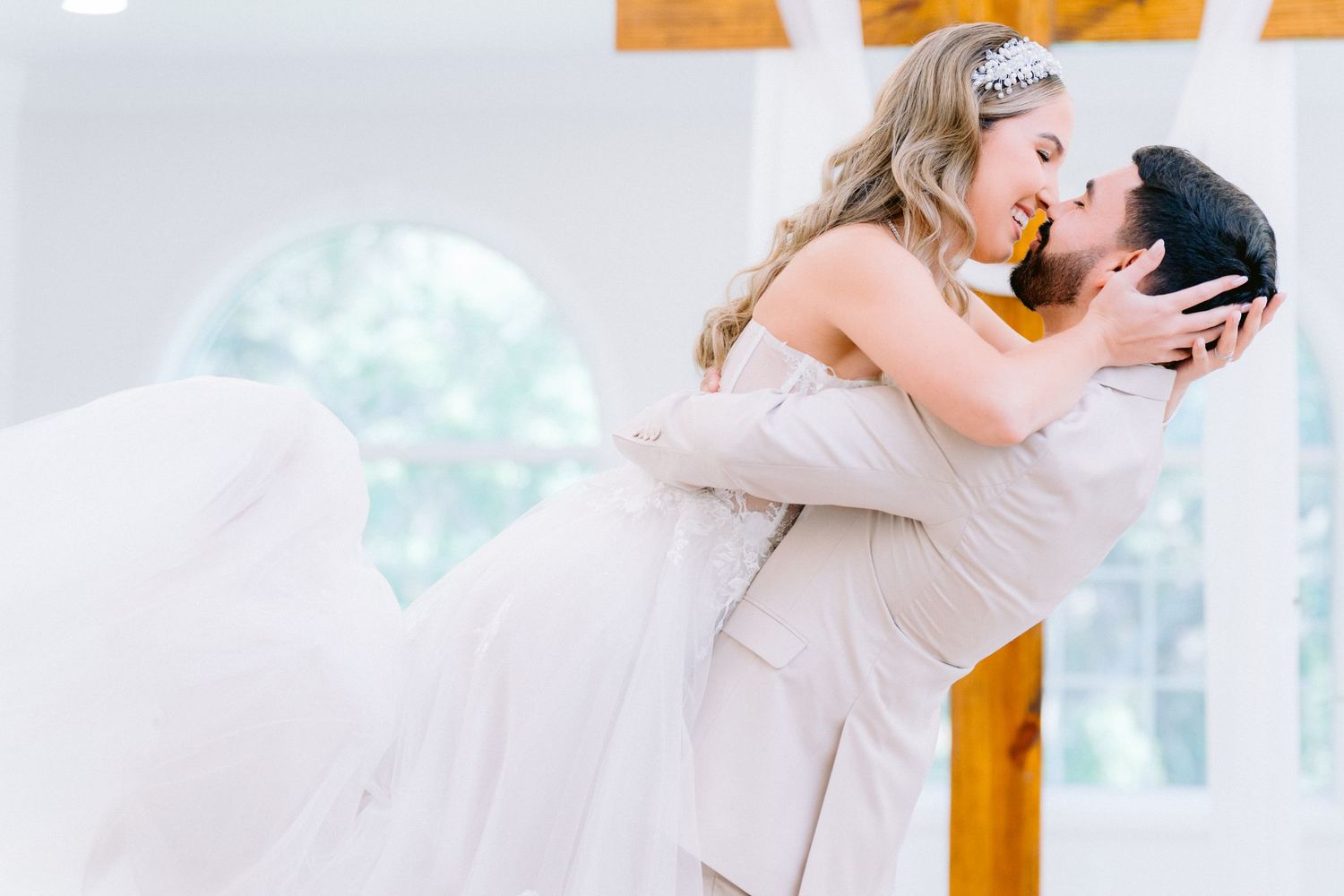 Wedding moment at Harborside Chapel, Safety Harbor, Tampa, Florida a joyful kiss while the groom lifts the bride in her flowing white dress.
