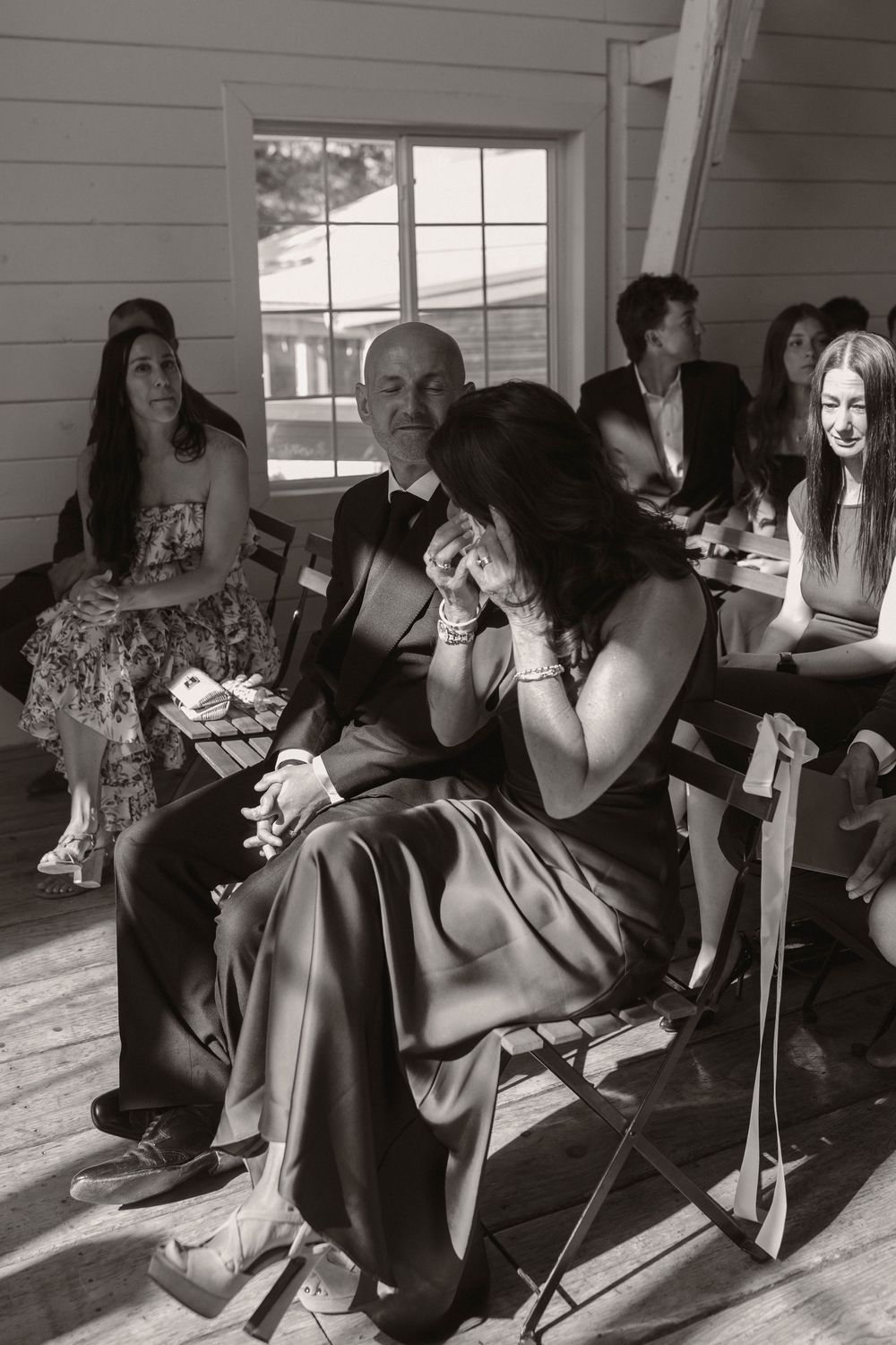 Wedding guests relaxing on chairs in a sunlit room during reception.