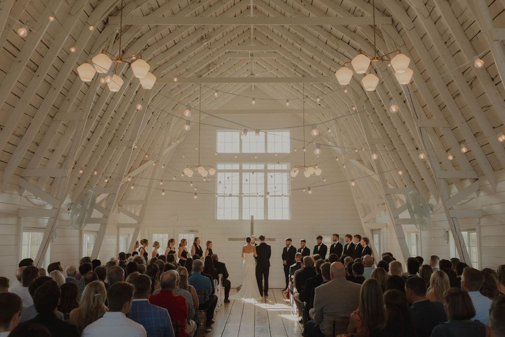 A bright, airy wedding venue with vaulted ceilings and hanging lights creates an elegant atmosphere.