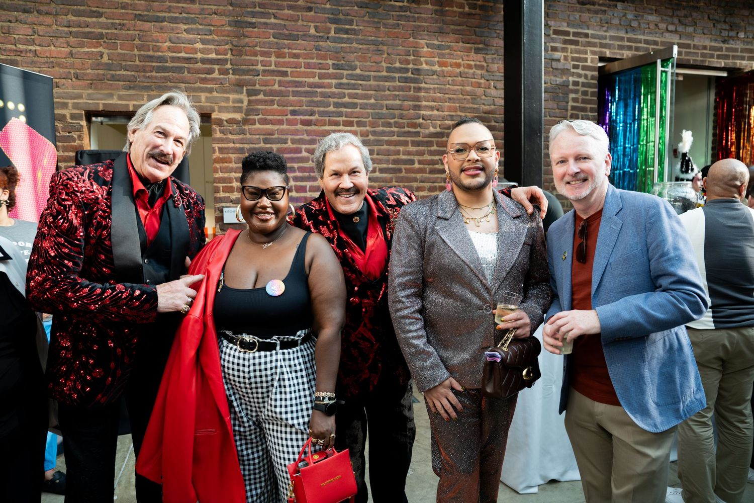 Group of creatives, singers and artists pose for a photo during the Gay for DC Theater. Formally dressed, notes of red, black and blue