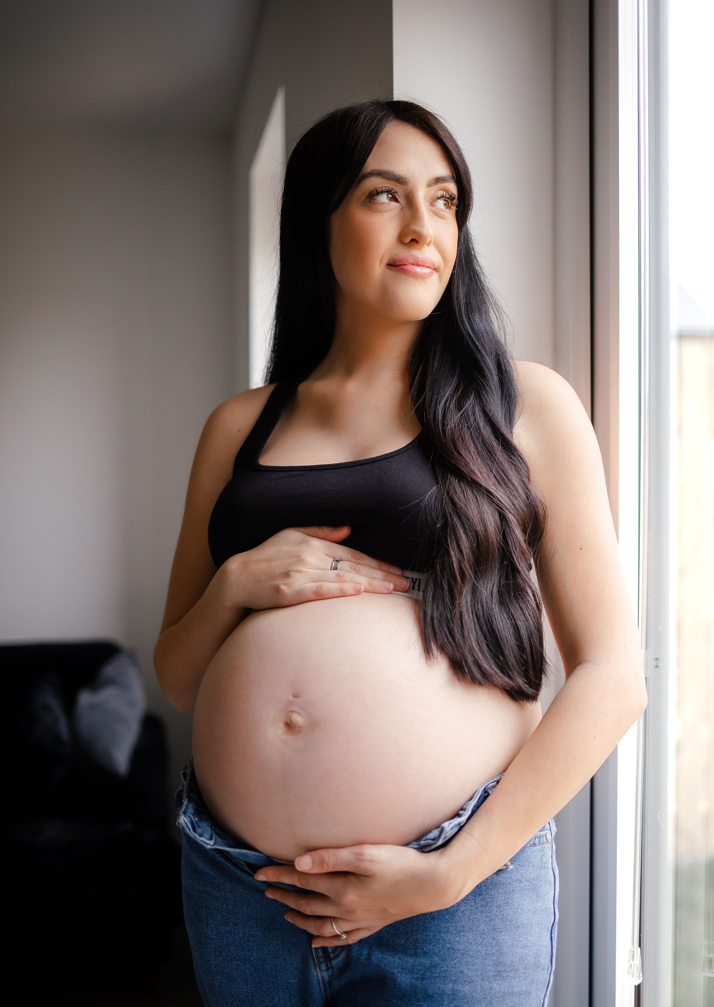 Indoor maternity family photoshoot with expecting mother holding her bump