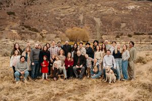 Large group gathered outdoors for family photo with mountains and desert brush in background.