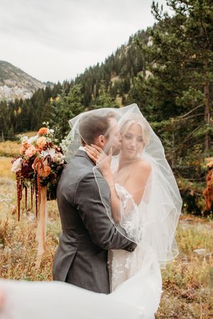 A romantic mountain wedding ceremony with fall floral arrangements and pine trees in the background.