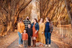 People walk on a path surrounded by fall foliage on a sunny autumn day in matching earth-tone outfits.