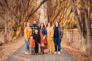 A group stands together on a path lined with autumn trees during a fall photo session.