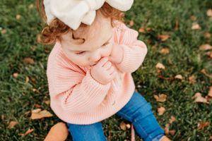 A series of autumn images showing a pink sweater against green grass and fallen leaves.