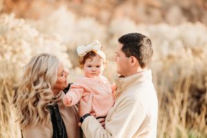 A sweet family photo session in a sunlit field with warm golden tones and soft natural lighting.