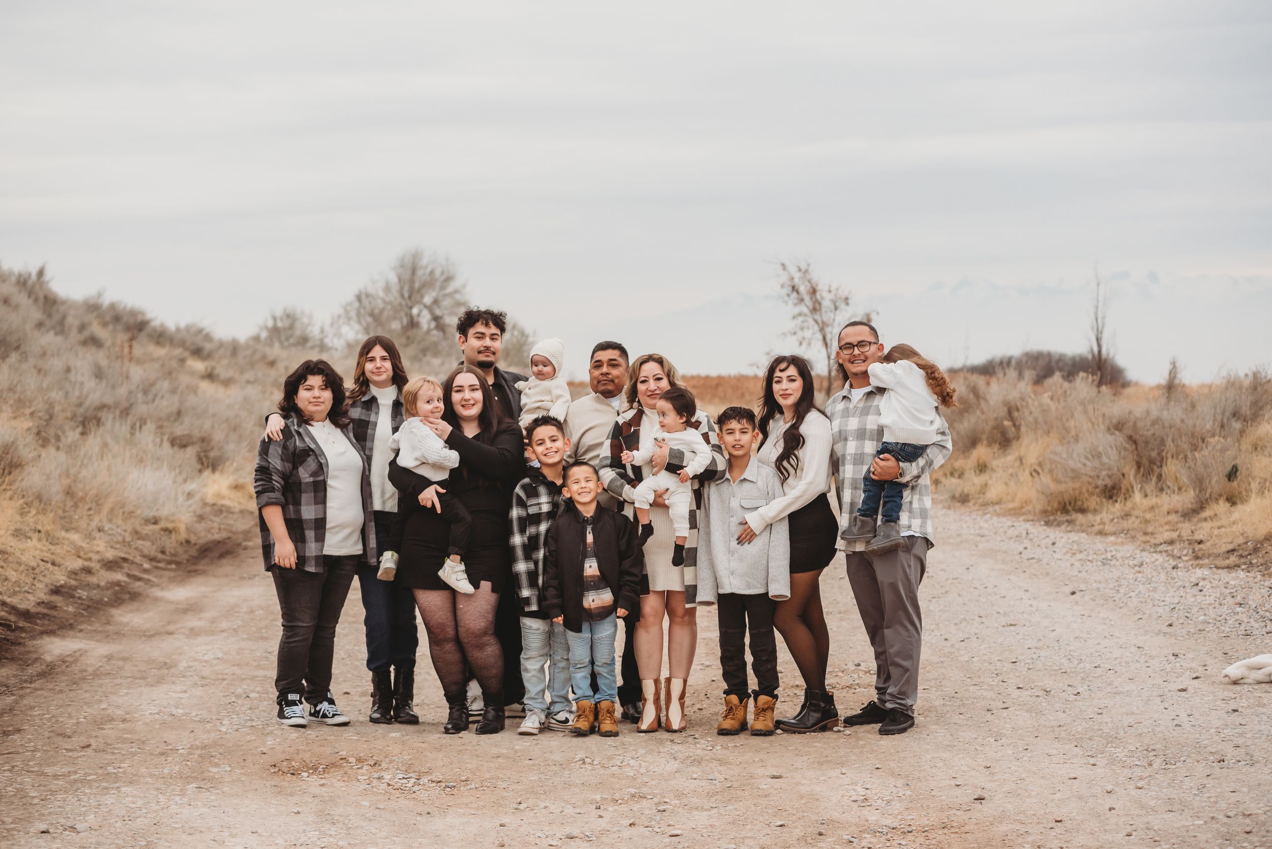 Happy people wearing earth tones and denim gather together on a desert path in natural sunlight.