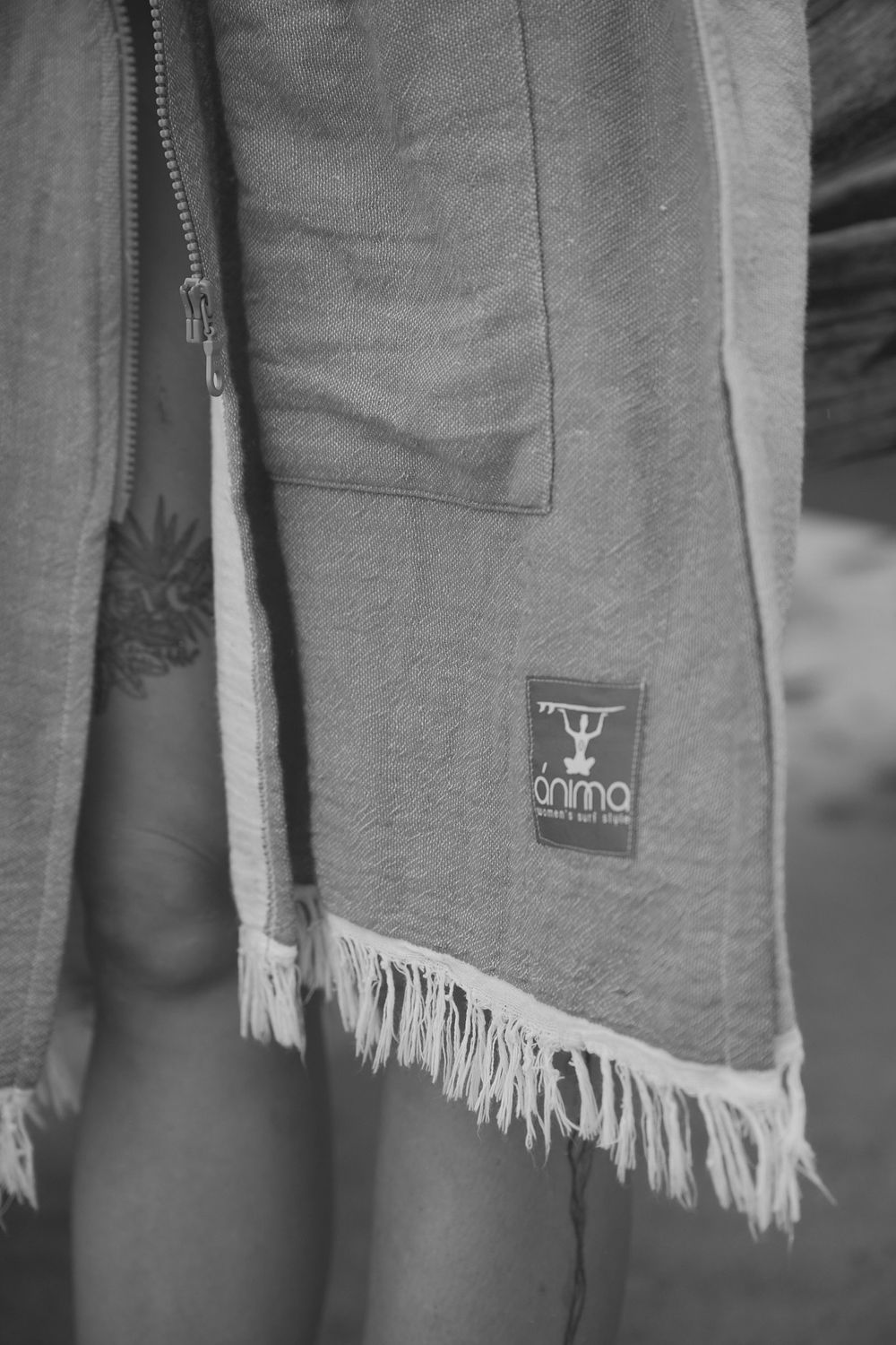 A close-up black and white photo of frayed fabric edges and a branded logo patch on casual clothing.