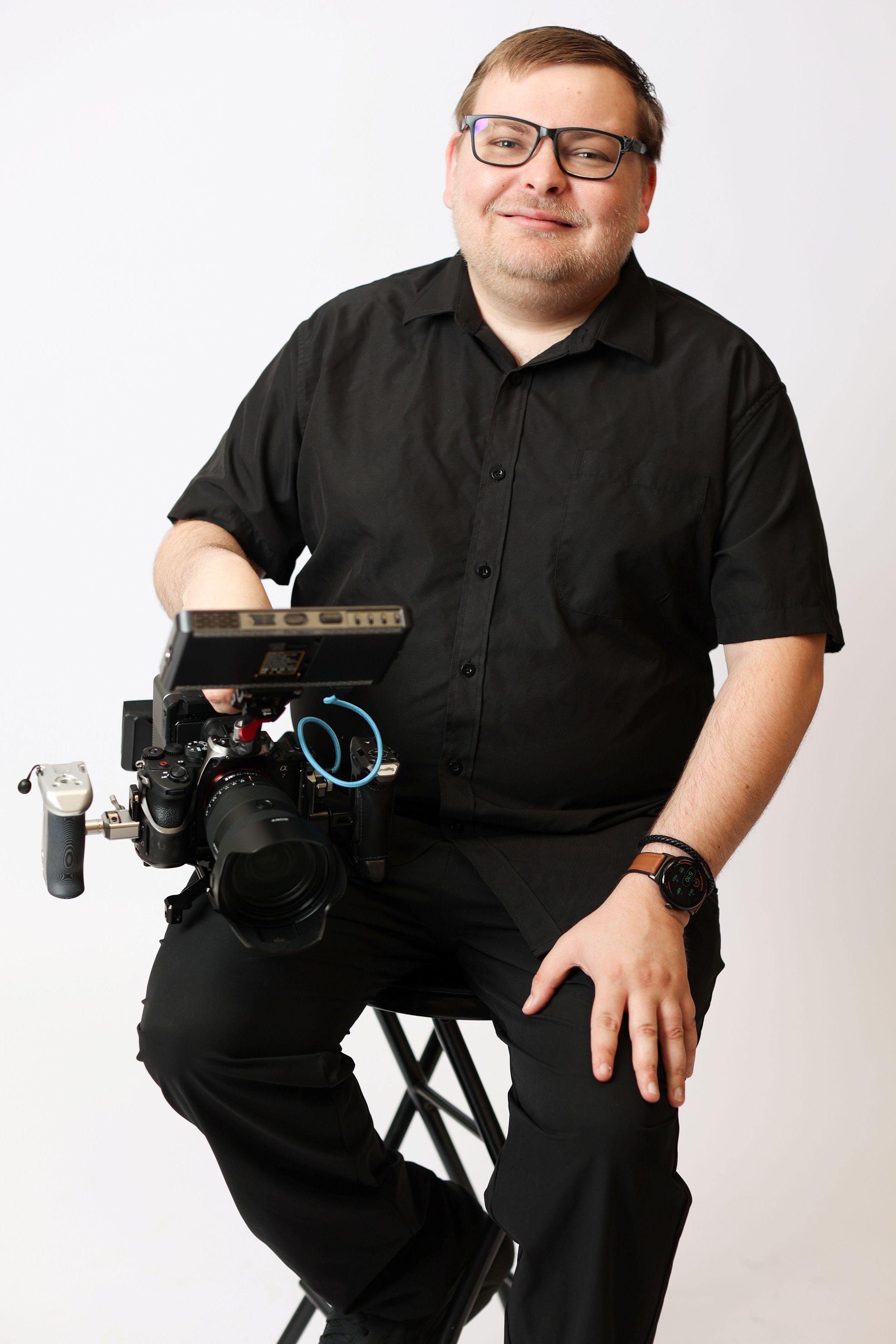 Owner Matt Wieters sitting on a stool holding a professional cinema camera rig.