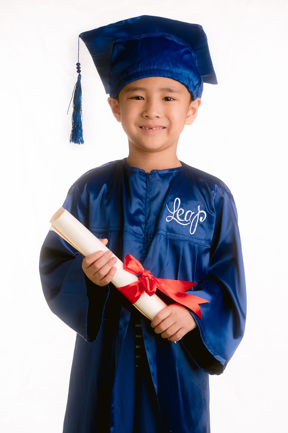 Graduate in navy blue cap and gown holds diploma with red ribbon at multiple angles against white background.