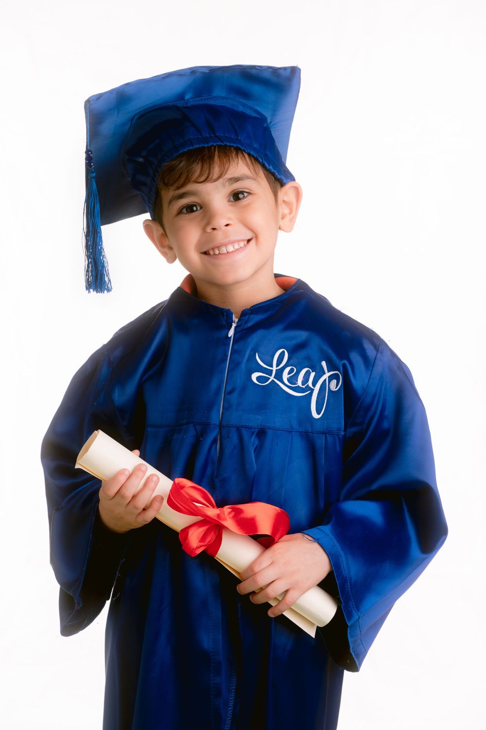 Close up of graduate in blue academic regalia showing a diploma tied with red ribbon.