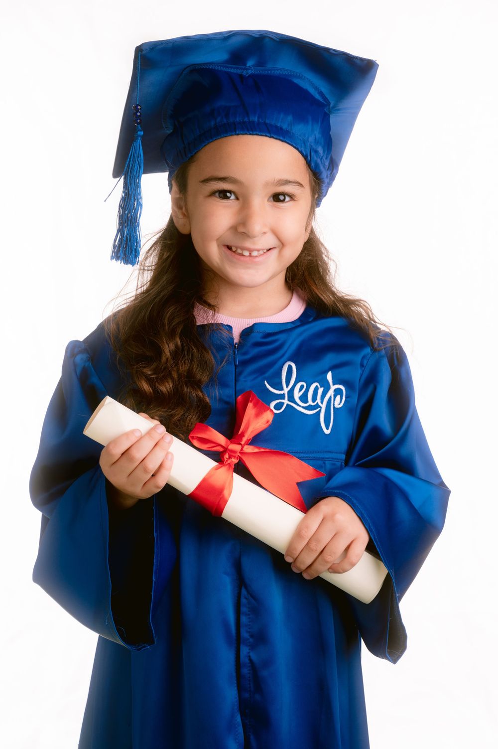 Young graduate in shiny blue cap and gown holds diploma with red ribbon during graduation photo session.