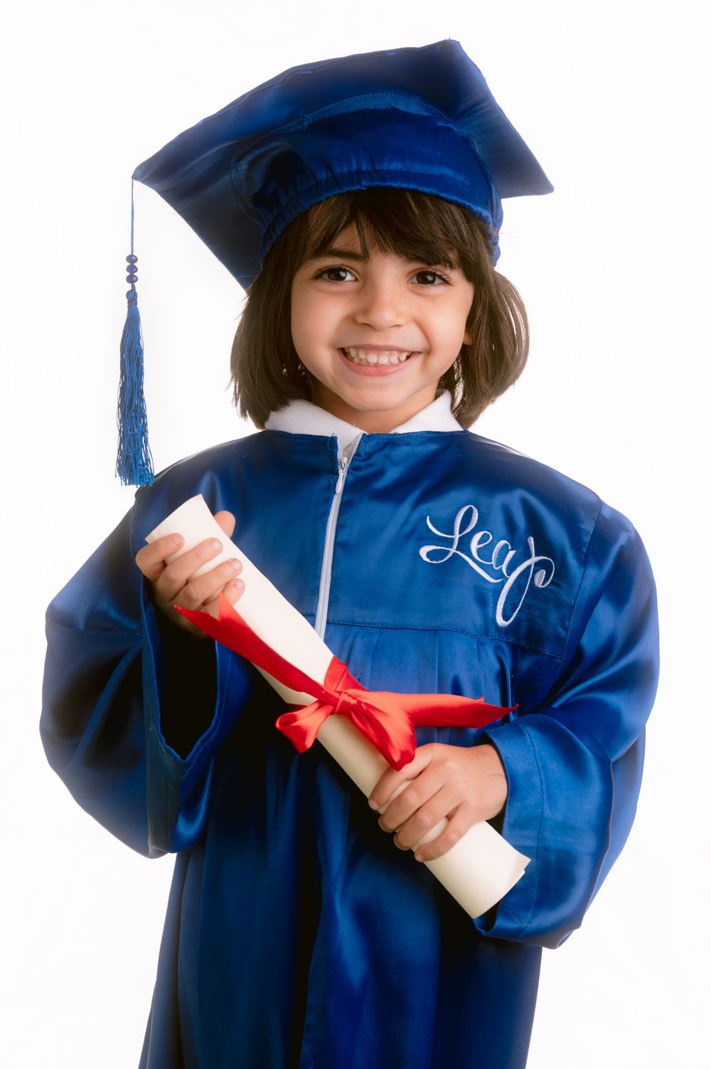 Graduate wearing bright blue commencement attire smiles while holding diploma with red bow.