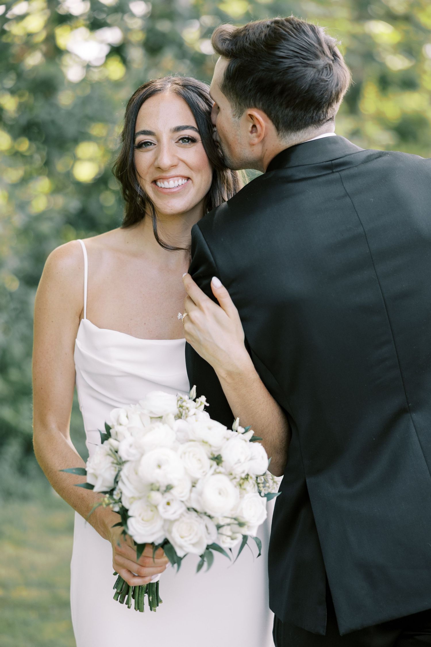 A romantic wedding moment outdoors with white bouquet of flowers and elegant minimalist bridal gown.
