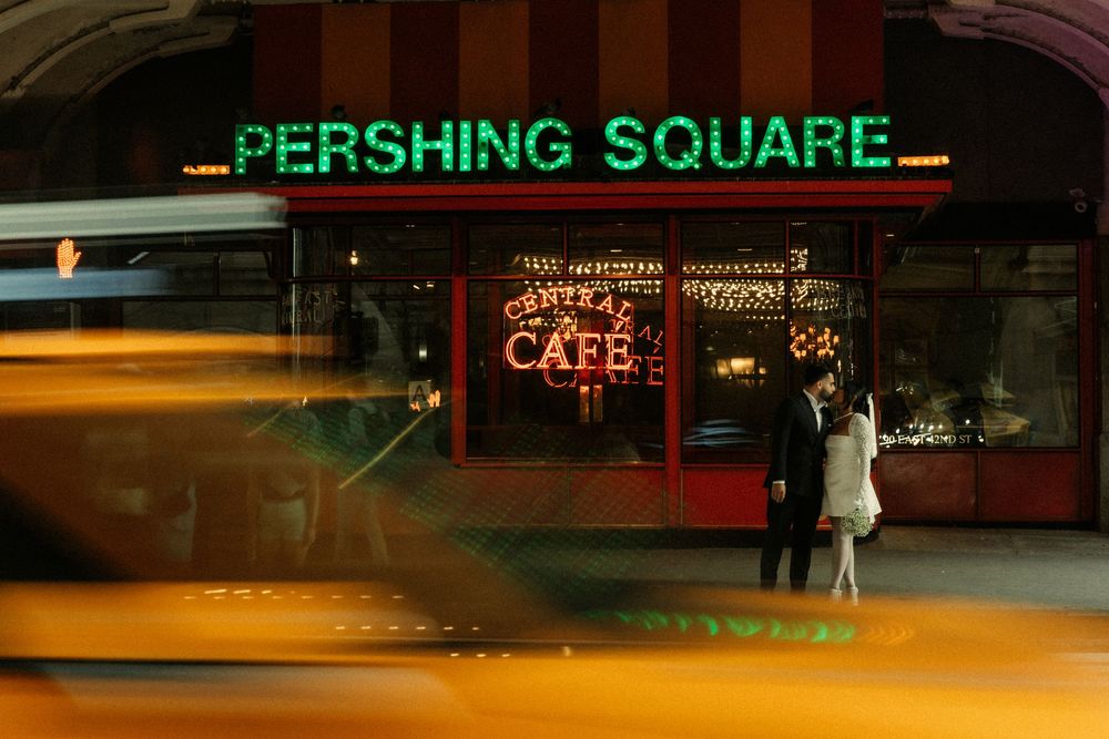 Green neon sign reading PERSHING SQUARE glows against dark urban night skyline in downtown Los Angeles.
