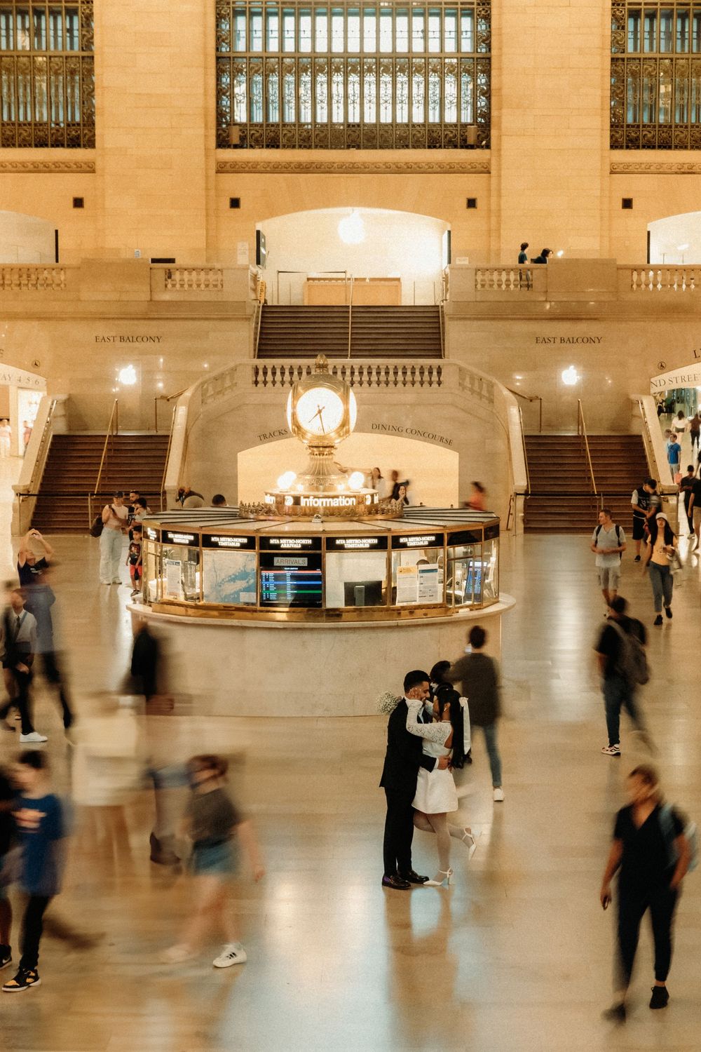 Motion-blurred commuters walking through the grand concourse of Grand Central Terminal in New York City.