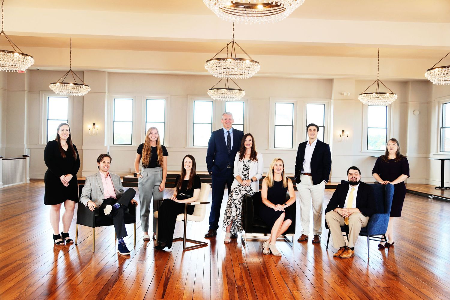 Business team posed in bright room with hardwood floors and elegant lighting.