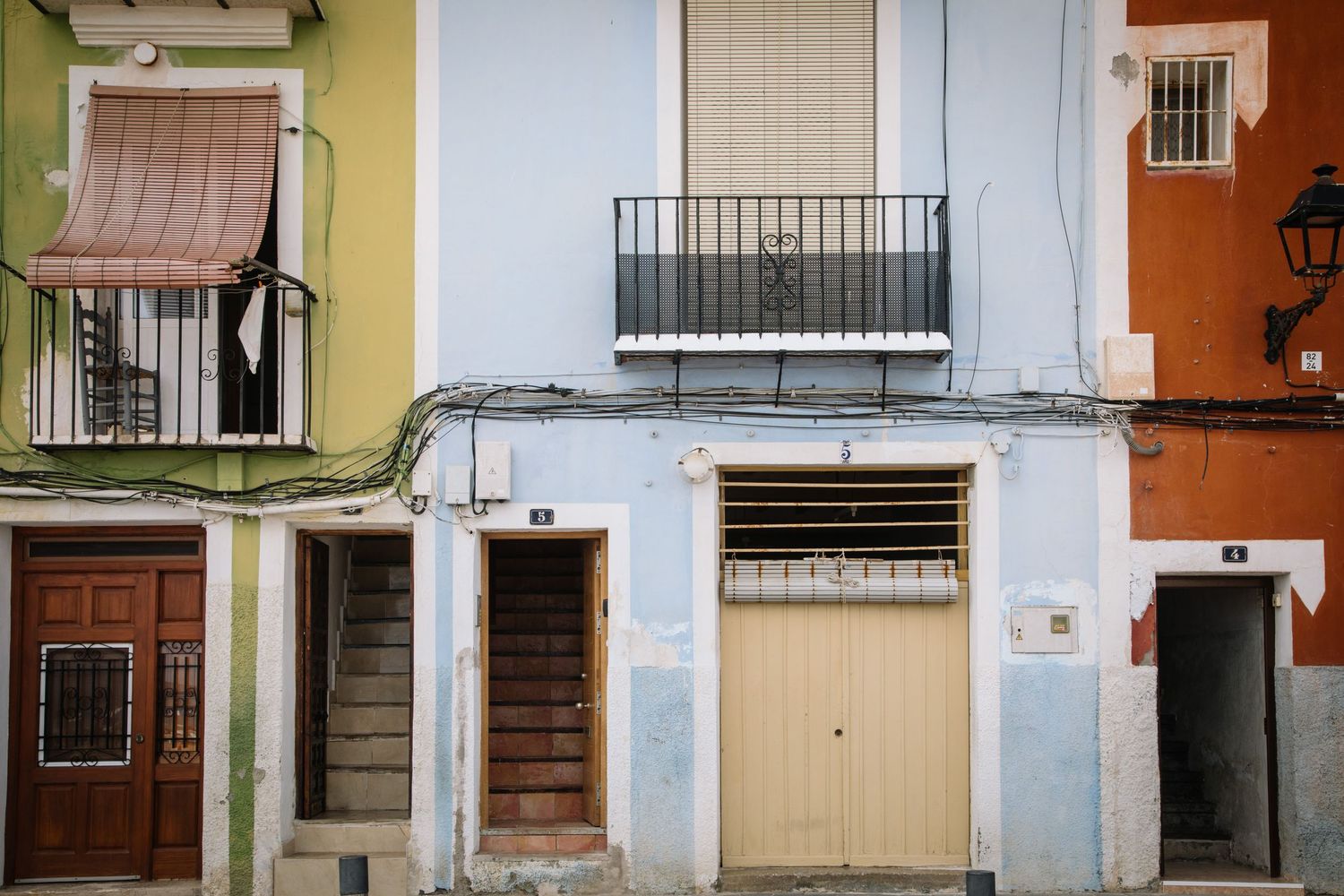 Colorful residential building facade with balconies and doors in Mediterranean style.