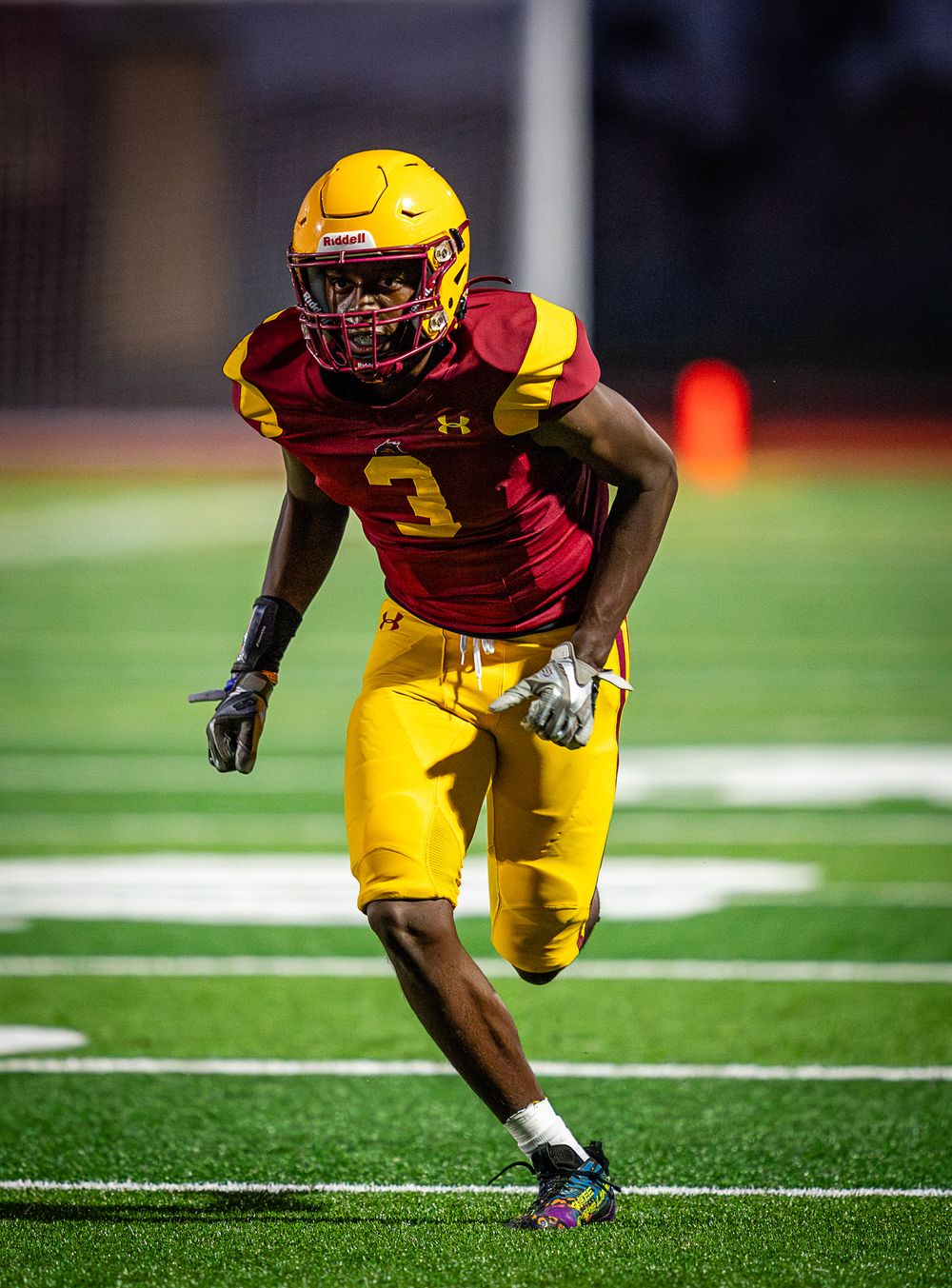 Football player in yellow uniform sprints across field during practice drill.