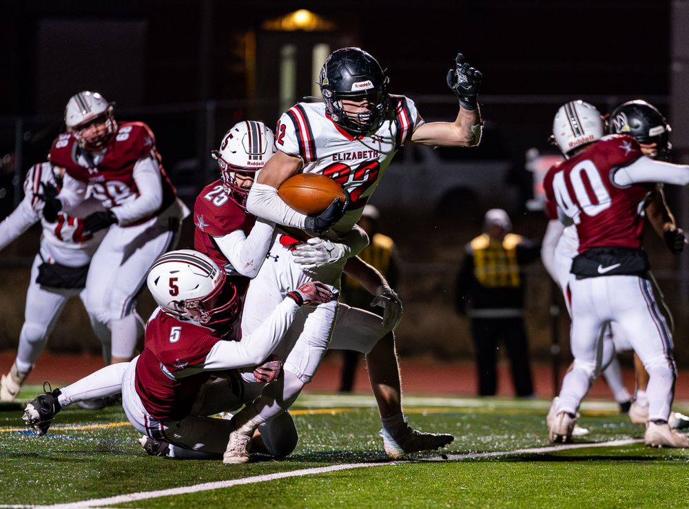 Football player leaps over defenders during dramatic rushing play.