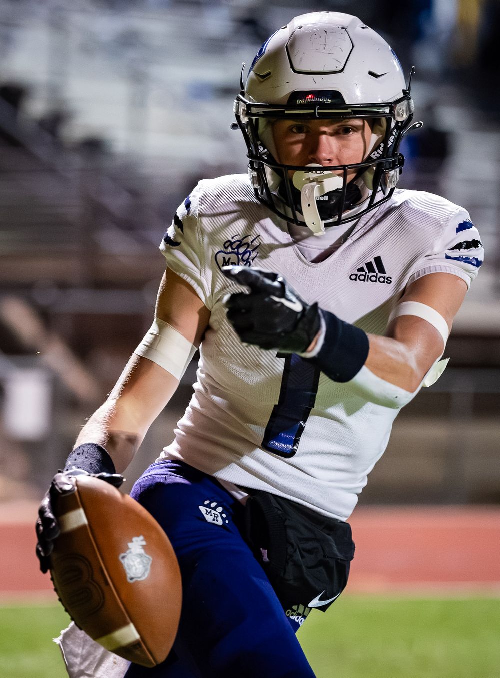 Football player in white uniform holds ball while celebrating during game.