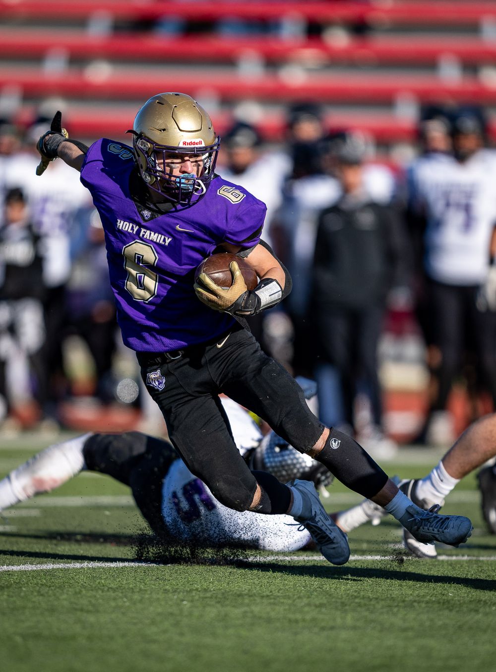 Football player in purple jersey breaks tackle while running with ball.