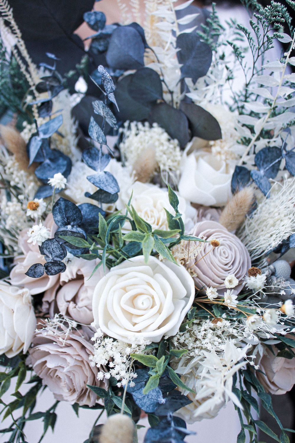 Wedding bouquet featuring blue and blush roses with delicate white accents.