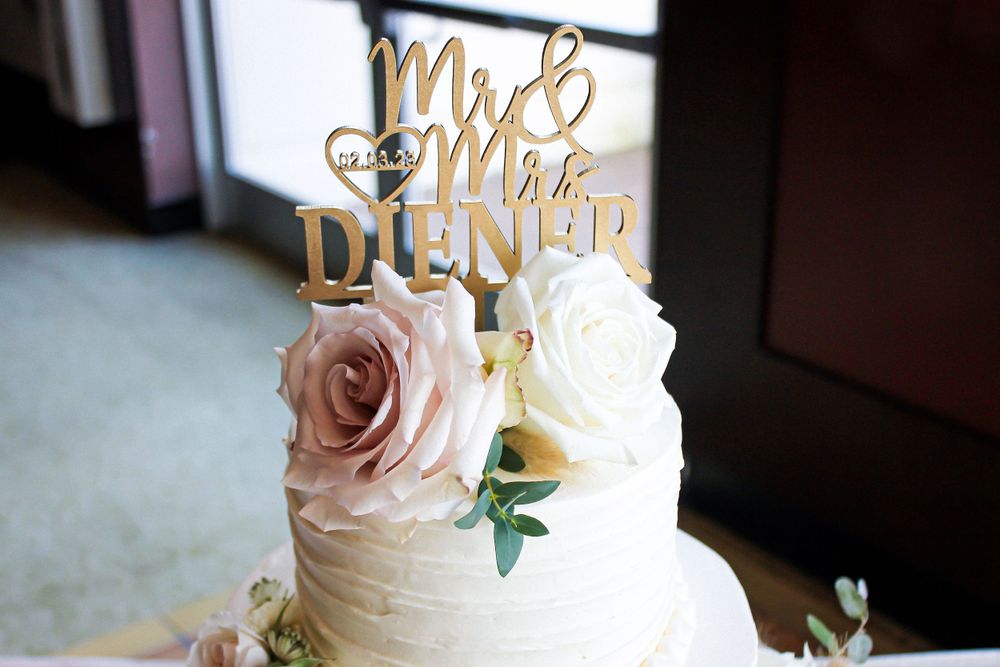 Wedding cake topped with gold Mr and Mrs Dunner sign and decorated with pink roses.